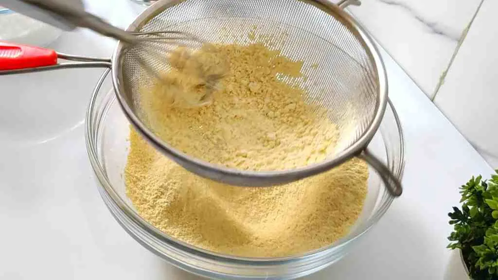Use a sifter to sift/seive the besan flour and remove all clumps.
In a pan, add 1 cup of ghee and 1 cup of oil. Bring the mixture to a boil and simmer.
In a separate large non-stick pan, add the sugar and water. Bring the mixture to a boil and stir until the sugar reaches a one string consistency. One string consistency is where you press the cooled sugar syrup between your thumb and index finger and a single string of sugar stretches out when you spread your thumb and finger apart. Keep the flame on low heat.
Slowly add the sieved gram flour to the sugar mixture in batches, while continuously stirring to avoid lumps.
Take a ladleful of the hot ghee-oil mixture and pour it into the besan mixture. Stir until the oil is completely absorbed. Repeat this process until no more oil and ghee mixture will be absorbed by the besan mixture.
Once the besan and sugar mixture is completely saturated with the ghee-oil mixture, transfer the mixture to a greased tray, loaf pan, or square pan. Press the mixture into the mold.
Allow the mixture to cool for 5 minutes before cutting into desired pieces witha. sharp knife. After 20 minutes, you can separate the pieces.
Your Mysore Pak is now ready to serve.